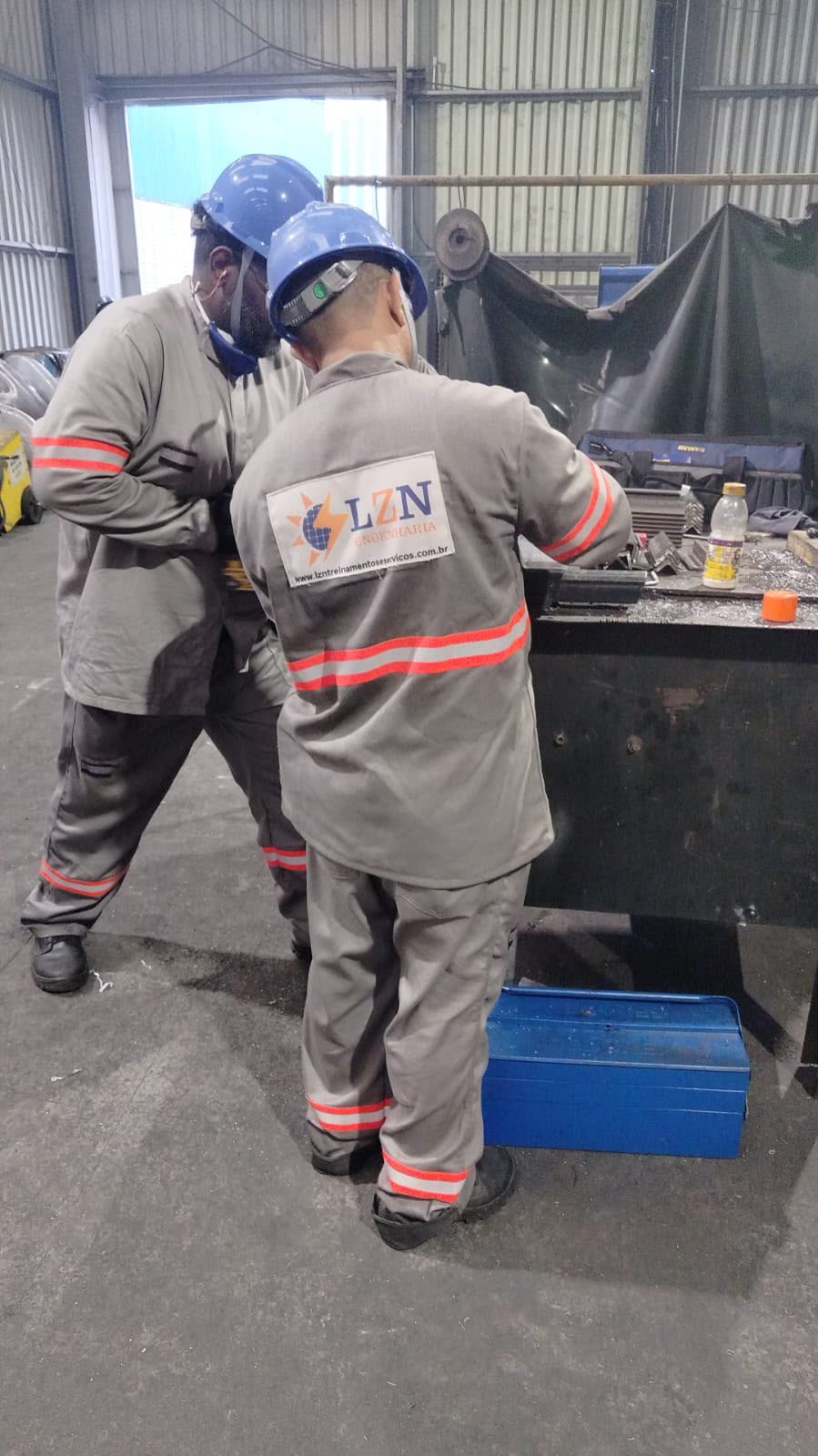 Dois profissionais da LZN Engenharia com capacete e uniforme da empresa em ambiente industrial